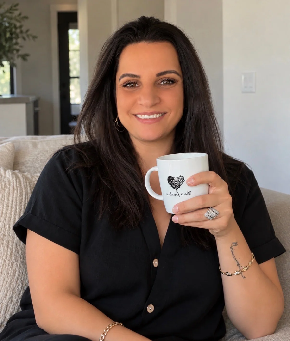 Christina smiling in a black shirt, holding her Do It For Them mug