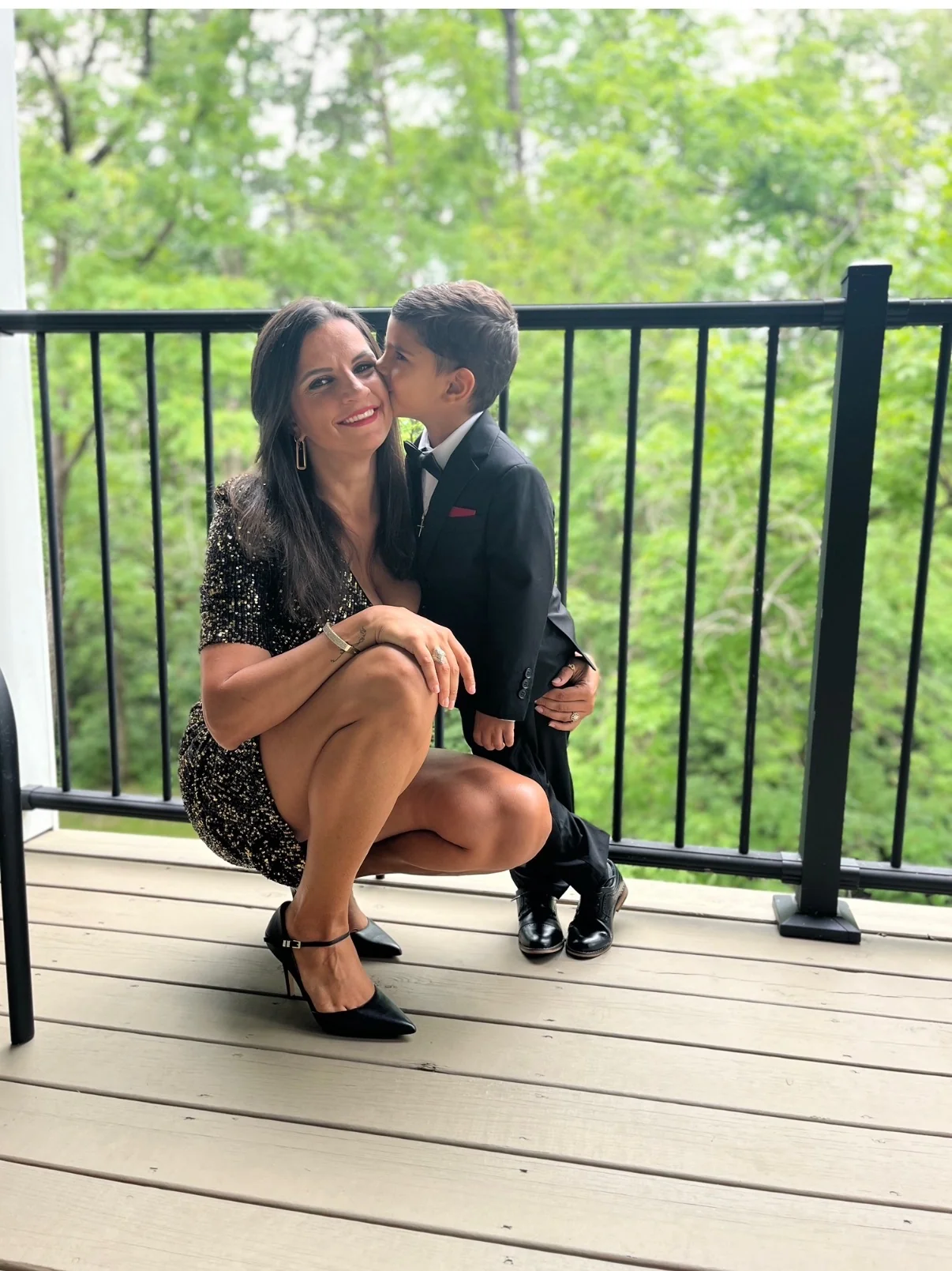 Christina smiling as her son kisses her cheek